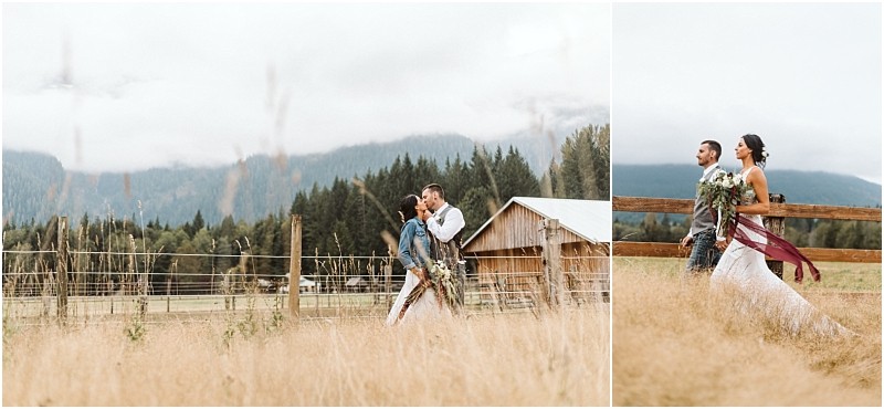 Premier snohomish & seattle wedding photographer | gsquared weddings photography a couple in wedding attire walks through a grassy field near a rustic barn in snohomish surrounded by mountains and trees on a cloudy day The bride holds a bouquet and wears a denim jacket in one imageperfect for a seattle wedding engagement session | serving snohomish seattle                   & beyond