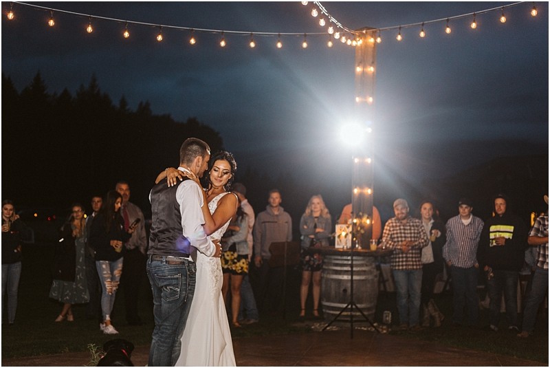Premier snohomish & seattle wedding photographer | gsquared weddings photography a bride and groom share their first dance outdoors at night under string lights at their snohomish wedding surrounded by guests who watch and smile The scene is warmly lit and festive with a rustic casual atmosphere | serving snohomish seattle                   & beyond