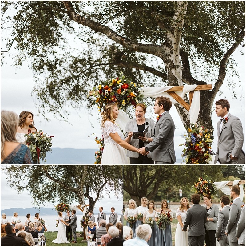 Premier snohomish & seattle wedding photographer | gsquared weddings photography a joyful couple exchanges vows under a floral arch outdoors at their snohomish seattle wedding framed by a large tree Guests are seated bridesmaids in blue and groomsmen in gray stand by The sky is overcast adding romance to the celebration | serving snohomish seattle                   & beyond