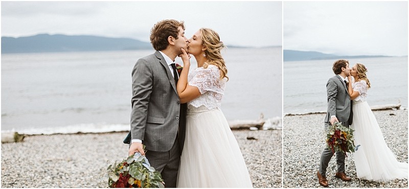 Premier snohomish & seattle wedding photographer | gsquared weddings photography a bride and groom share a kiss on a rocky beach near snohomish with the ocean and mountains behind them The groom in a gray suit holding a bouquet stands with his bride in a white gown under the cloudy seattle sky | serving snohomish seattle                   & beyond