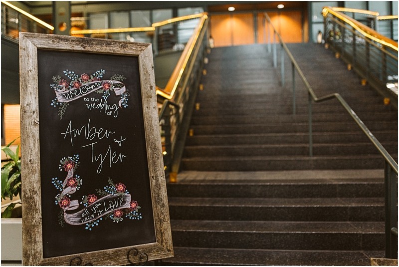 Premier snohomish & seattle wedding photographer | gsquared weddings photography a chalkboard wedding sign with floral decorations reads welcome to the wedding of amber & tyler all you need is love and stands at the base of wide carpeted stairsperfect for a romantic snohomish seattle wedding or engagement celebration | serving snohomish seattle                   & beyond