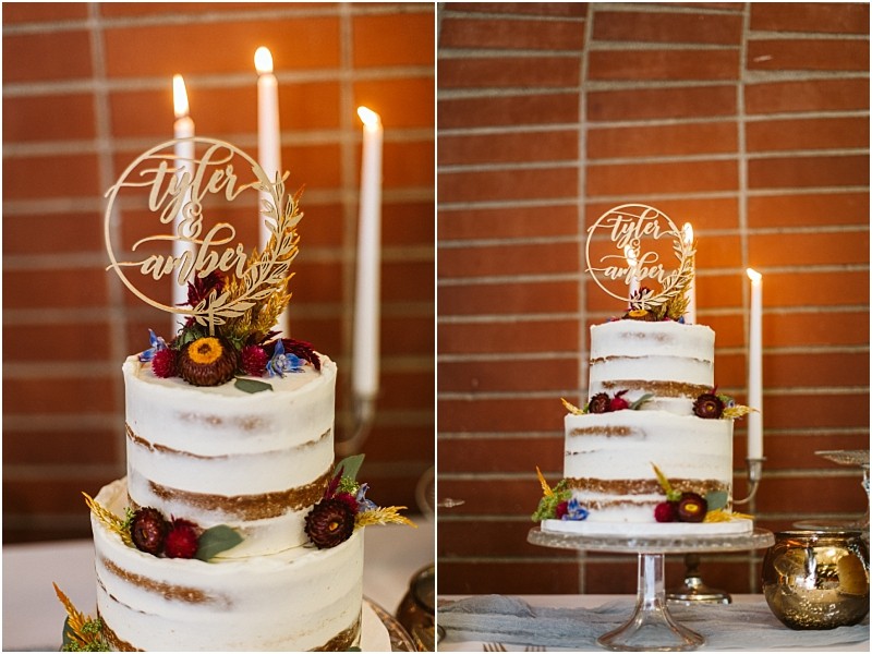 Premier snohomish & seattle wedding photographer | gsquared weddings photography a two tier semi naked cake perfect for a snohomish or seattle wedding is decorated with flowers and greenery on a glass stand The topper reads tyler & amber with glowing candles against a brick wall in the background | serving snohomish seattle                   & beyond