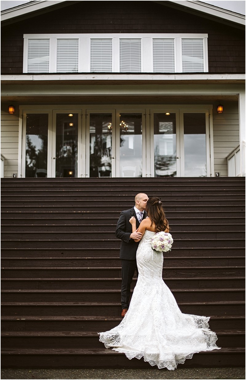 Premier snohomish & seattle wedding photographer | gsquared weddings photography a bride in a white lace gown holding a bouquet stands on outdoor steps facing her groom in a dark suit They look at each other in front of a large building with glass doors and white trim at their snohomish seattle wedding | serving snohomish seattle                   & beyond