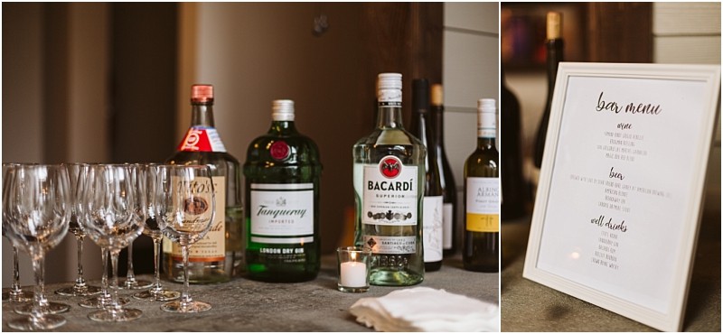 Premier snohomish & seattle wedding photographer | gsquared weddings photography a selection of liquor bottles wine and empty glasses are arranged on a counter at this snohomish wedding Next to them is a framed bar menu listing available drinks along with a small candle and a stack of napkins | serving snohomish seattle                   & beyond