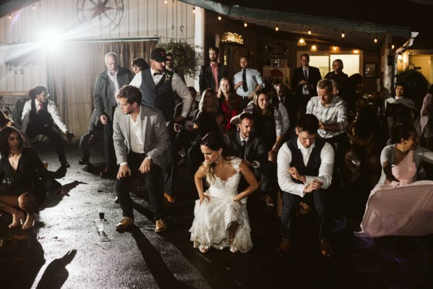 Premier snohomish & seattle wedding photographer | gsquared weddings photography a bride in a white dress leads snohomish wedding guests in a coordinated dance outdoors at night their joyful expressions shining beneath festive lightsa perfect seattle engagement celebration | serving snohomish seattle                   & beyond
