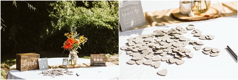 Premier snohomish & seattle wedding photographer | gsquared weddings photography a snohomish wedding guest book table outdoors features a wooden card box a mason jar with orange and yellow flowers a small sign and scattered wooden hearts on a white tablecloth in sunlight | serving snohomish seattle                   & beyond