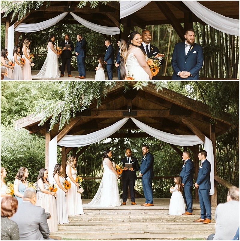 Premier snohomish & seattle wedding photographer | gsquared weddings photography a romantic snohomish wedding ceremony unfolds outdoors under a wooden pavilion with white drapery The bride and groom stand facing each other surrounded by their wedding party and guests with lush greenery enhancing this seattle engagement moment | serving snohomish seattle                   & beyond