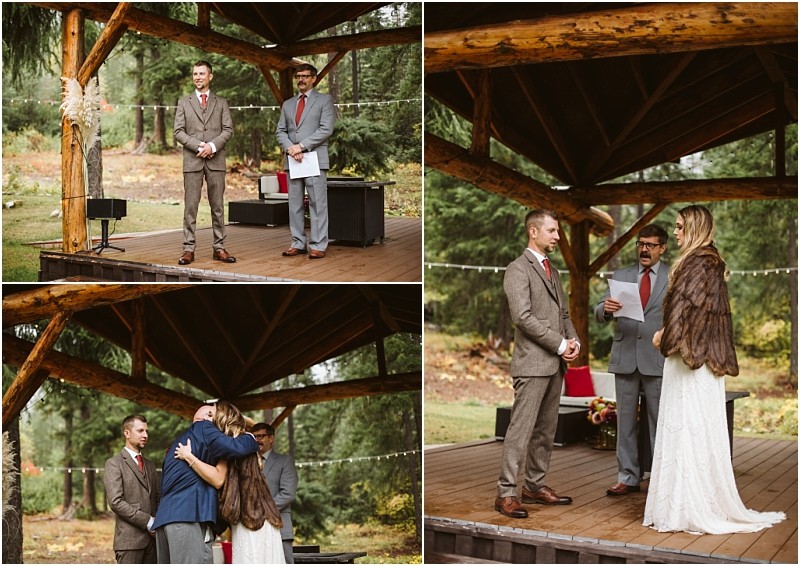 Premier snohomish & seattle wedding photographer | gsquared weddings photography a bride in a fur shawl and a groom in a brown suit stand with an officiant on a wooden outdoor stage in a forest This snohomish wedding unfolds as the couple listens hugs and exchanges vows beneath a rustic wooden pavilion | serving snohomish seattle                   & beyond