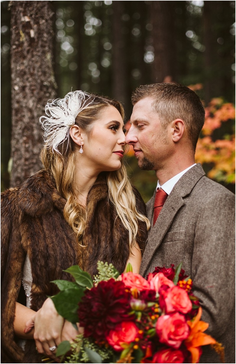 Premier snohomish & seattle wedding photographer | gsquared weddings photography a bride and groom stand close together in a forest during their snohomish wedding the bride wears a fur shawl feather hair accessory and holds a vibrant bouquet The groom complements her with a brown suit and red tie | serving snohomish seattle                   & beyond