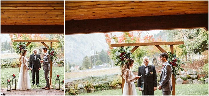 Premier snohomish & seattle wedding photographer | gsquared weddings photography a bride and groom stand facing each other under a wooden arch with flowers during a snohomish outdoor wedding ceremony with an officiant between them and mountains visible in the background | serving snohomish seattle                   & beyond