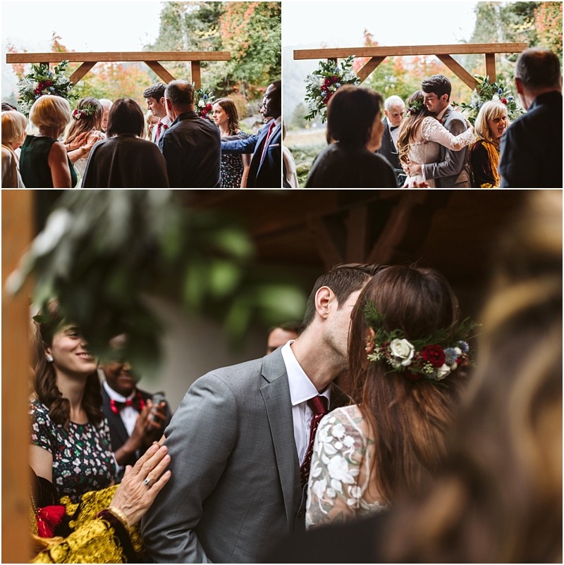 Premier snohomish & seattle wedding photographer | gsquared weddings photography a bride and groom kiss under a wooden archway decorated with flowers surrounded by guests who are smiling clapping and celebrating their snohomish wedding ceremony | serving snohomish seattle                   & beyond