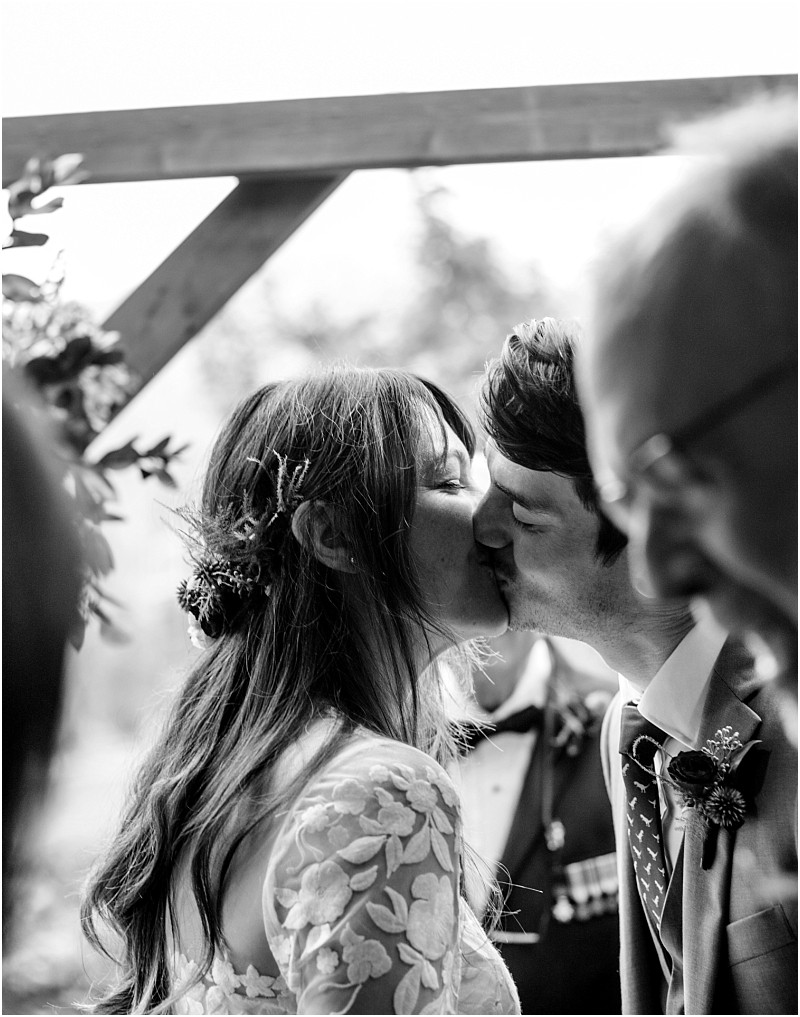 Premier snohomish & seattle wedding photographer | gsquared weddings photography a bride and groom share a kiss during their snohomish wedding ceremony surrounded by loved ones The black and white image captures an intimate and joyful moment in the heart of seattles wedding scene | serving snohomish seattle                   & beyond