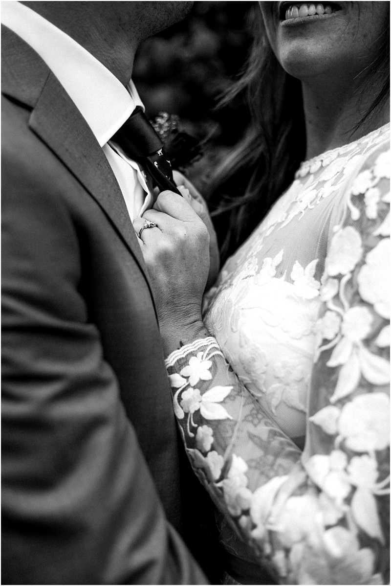 Premier snohomish & seattle wedding photographer | gsquared weddings photography black and white close up of a couple in wedding attire with the bride smiling and holding the grooms tie Her lace dress and engagement ring stand out Capturing a timeless snohomish seattle wedding moment their faces are mostly out of frame | serving snohomish seattle                   & beyond