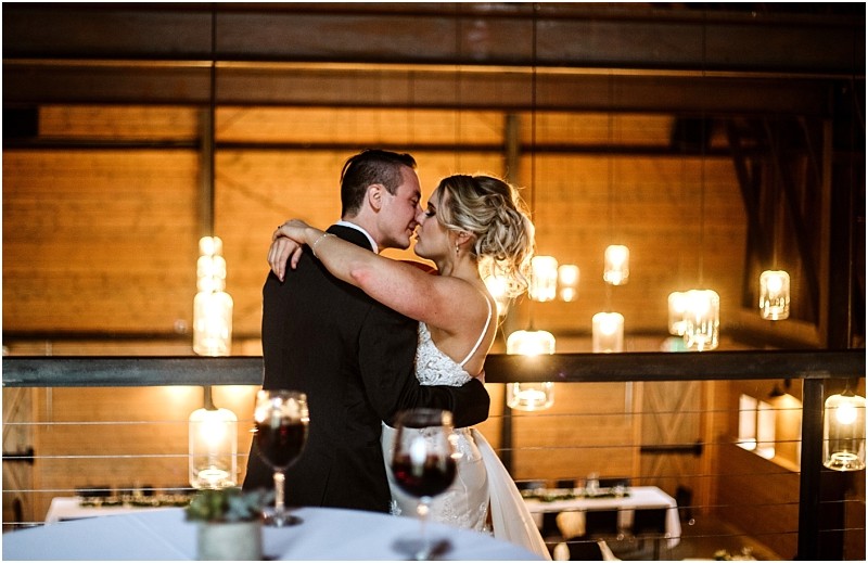 Premier snohomish & seattle wedding photographer | gsquared weddings photography a bride and groom embrace and share an intimate moment on a balcony at their snohomish wedding surrounded by warm hanging lights and soft romantic ambiance A table with wine glasses is in the foreground | serving snohomish seattle                   & beyond