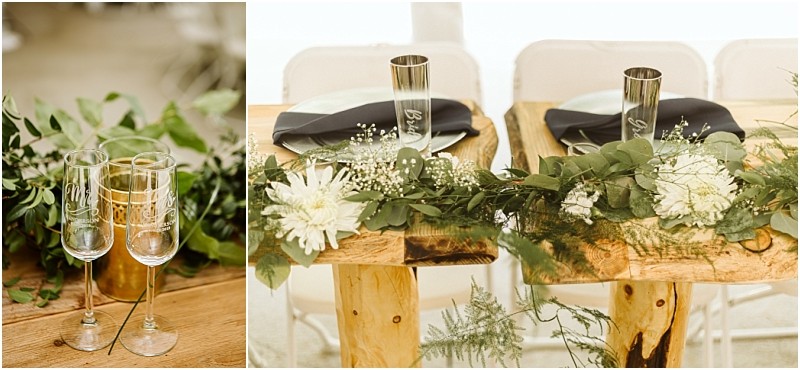 Premier snohomish & seattle wedding photographer | gsquared weddings photography two wooden tables with rustic decor greenery white flowers and black napkins set the scene for a snohomish seattle wedding Two engraved champagne flutes rest on one table with simple chairs arranged behind for an intimate celebration | serving snohomish seattle                   & beyond
