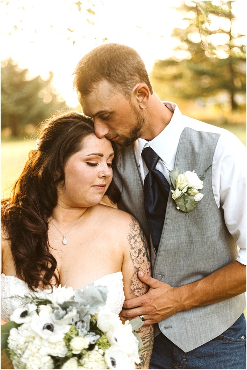Snohomish & seattle wedding photographer | gsquared weddings photography a groom in a gray vest kisses the forehead of his bride who holds a white bouquet This tender outdoor moment bathed in warm sunlight beautifully captures wedding couples at their best of 2019 | wedding photo by gsquared weddings