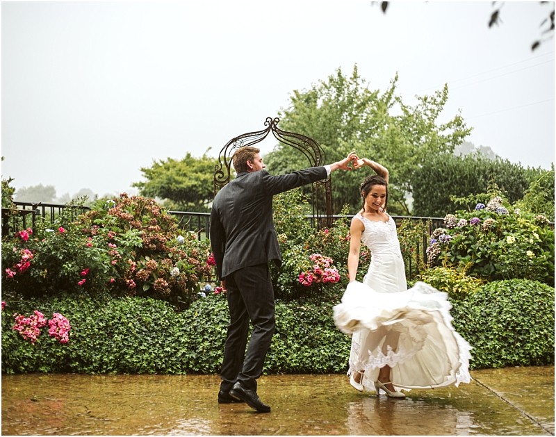 Snohomish & seattle wedding photographer | gsquared weddings photography a bride and groom dance joyfully in the rain on a garden patio surrounded by colorful blooming flowers and greenerycapturing pure happiness in this wedding couples moment truly one of the best of 2019 | wedding photo by gsquared weddings