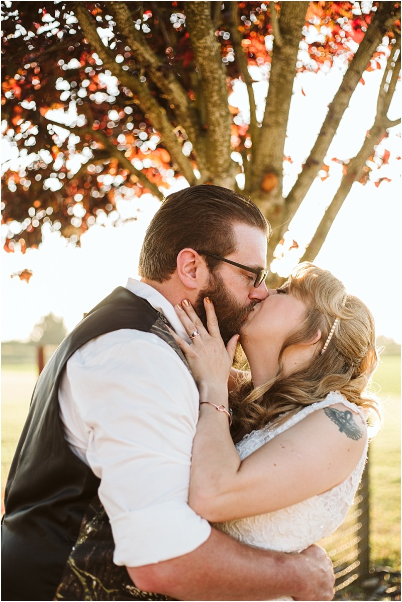 Snohomish & seattle wedding photographer | gsquared weddings photography a couple dressed in wedding attire shares a passionate kiss outdoors beneath a tree with sunlit red leaves embracing joyfully This romantic moment captures the essence of wedding couples at their best of 2019 | wedding photo by gsquared weddings