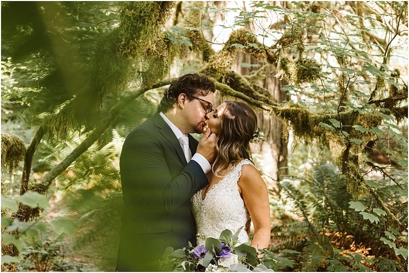 Snohomish & seattle wedding photographer | gsquared weddings photography a bride and groom share a romantic kiss in a lush green forest The groom gently holds the brides chin as she clutches her bouquet Moss covered branches surround the wedding couple creating an intimate natural best of 2019 setting | wedding photo by gsquared weddings