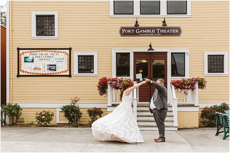 Snohomish & seattle wedding photographer | gsquared weddings photography a bride and groom one of our best of 2019 wedding couples dance together outside port gamble theater a yellow building with flower boxes and a large sign above the entrance The brides dress twirls as the groom lifts her arm | wedding photo by gsquared weddings
