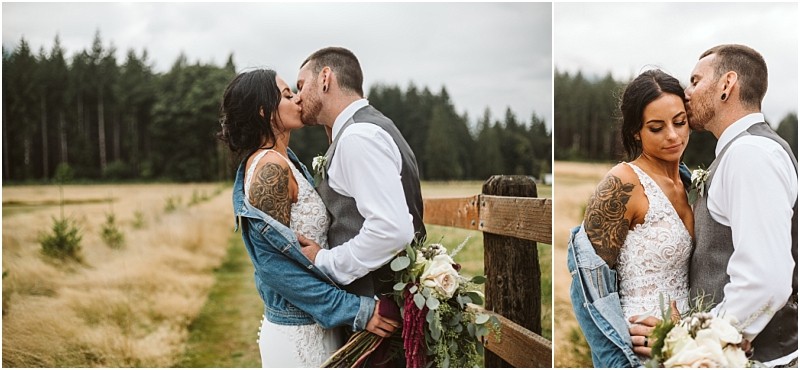 Snohomish & seattle wedding photographer | gsquared weddings photography one of our best of 2019 wedding couples kisses and embraces outdoors by a wooden fence with scenic fields and trees behind them The bride in a lace dress and denim jacket holds a bouquet the groom wears a vest and white shirt | wedding photo by gsquared weddings