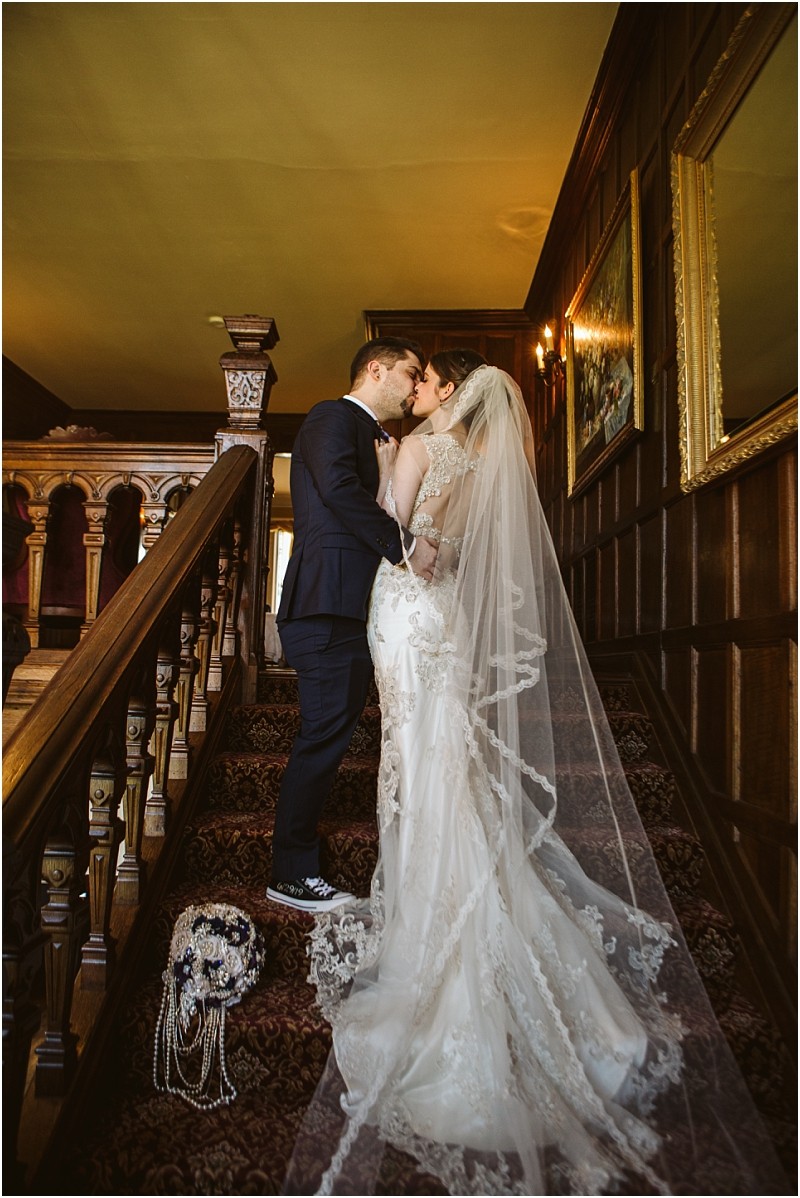 Snohomish & seattle wedding photographer | gsquared weddings photography a bride and groom share a kiss on a carpeted staircase inside a wood paneled building This romantic moment captured among the best of 2019 wedding couples features her lace gown and his dark suit beside a bouquet on the steps | wedding photo by gsquared weddings