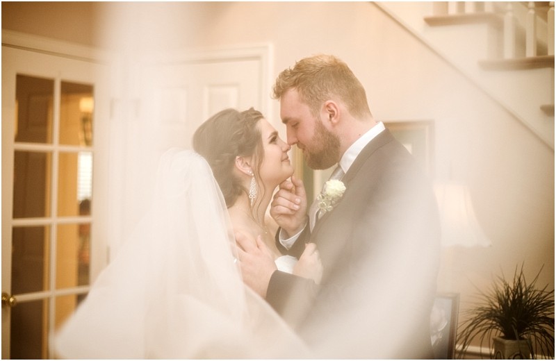 Snohomish & seattle wedding photographer | gsquared weddings photography a bride and groom embrace and smile softly touching noses in a warmly lit indoor setting at their marysville wedding The bride wears a veil and earrings while the groom dons a suit with a boutonniere in this dreamy romantic scene | wedding photo by gsquared weddings