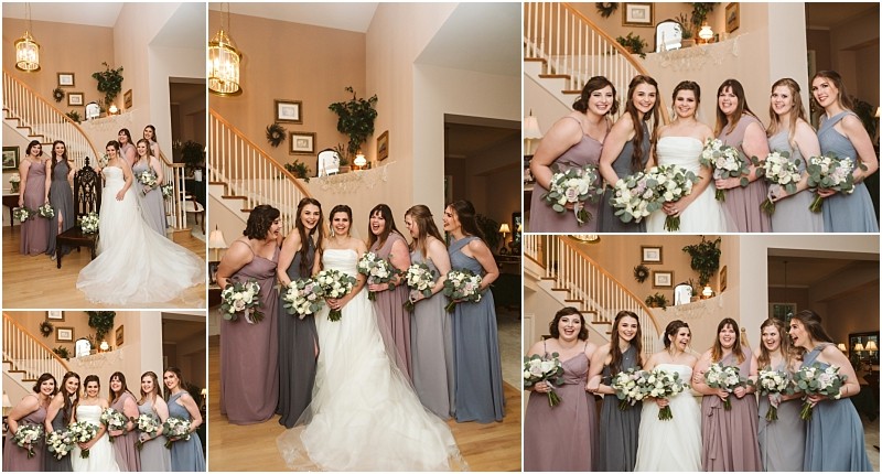 Snohomish & seattle wedding photographer | gsquared weddings photography a bride in a white gown poses indoors with five bridesmaids in purple and gray dresses holding bouquets and smiling together in front of a staircase during a warmly lit marysville wedding | wedding photo by gsquared weddings