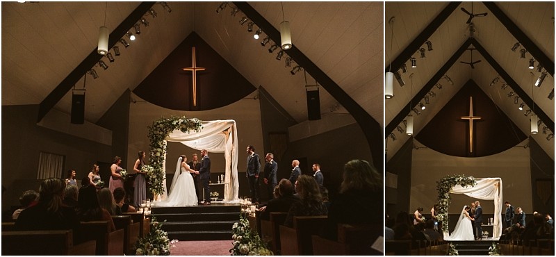Snohomish & seattle wedding photographer | gsquared weddings photography a marysville wedding ceremony in a church where a couple stands under a floral arch on stage flanked by their wedding party Guests fill the pews as a large illuminated cross shines above the scene | wedding photo by gsquared weddings