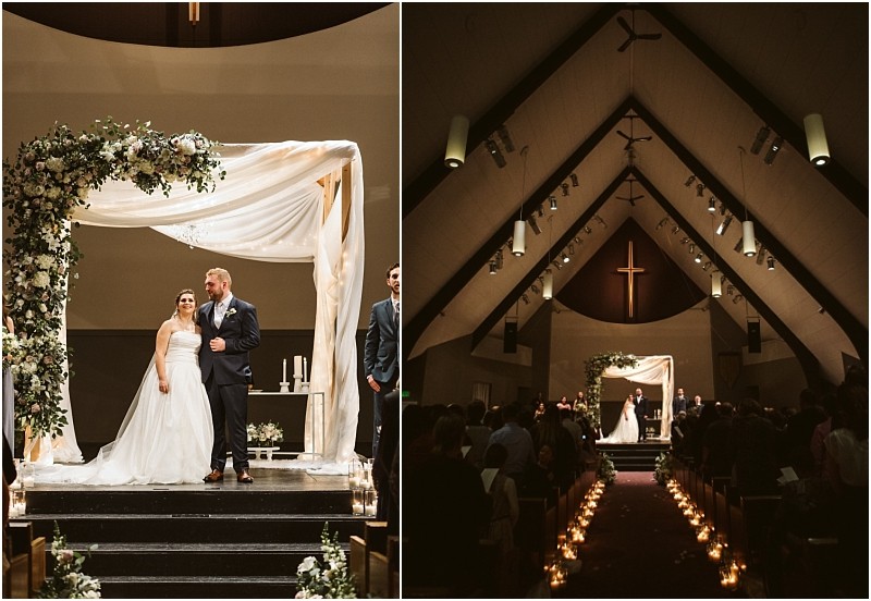 Snohomish & seattle wedding photographer | gsquared weddings photography a bride and groom stand under a floral arch inside a church at their marysville wedding On the right guests seated along an aisle lined with candles watch the couple at the altar beneath a large cross | wedding photo by gsquared weddings