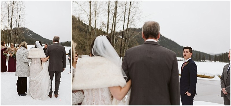 Snohomish & seattle wedding photographer | gsquared weddings photography a bride in a white dress and fur shawl walks on snow beside an older man approaching a groom in a suit who waits with others at an outdoor leavenworth wedding by a lake with mountains in the background | wedding photo by gsquared weddings
