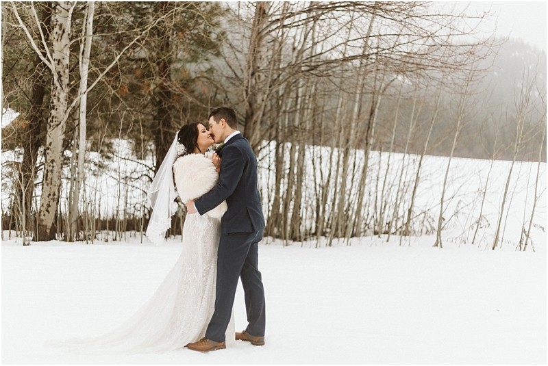 Snohomish & seattle wedding photographer | gsquared weddings photography a bride and groom share an intimate moment embracing in the snow before leafless trees The brides white gown and veil and the grooms blue suit add elegance to this serene foggy leavenworth wedding landscape | wedding photo by gsquared weddings