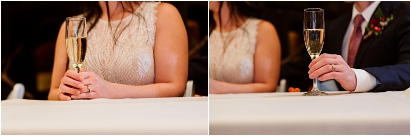 Snohomish & seattle wedding photographer | gsquared weddings photography close up of two people at a table during a leavenworth wedding each holding a champagne glass one in a lace dress the other in a suit with a red tie and boutonniere Only their hands and torsos are visible | wedding photo by gsquared weddings