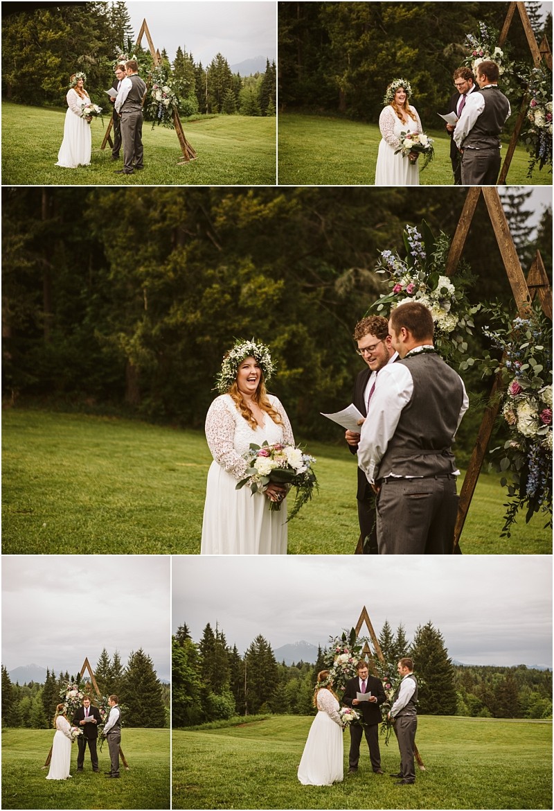 Snohomish & seattle wedding photographer | gsquared weddings photography a bride and groom stand with an officiant outdoors on a grassy field surrounded by trees and mountains sharing love with a view during their machias elopement by a wooden triangular arch decorated with flowers | wedding photo by gsquared weddings