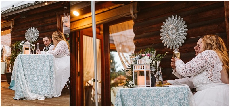 Snohomish & seattle wedding photographer | gsquared weddings photography a bride and groom sit together at a table with a blue patterned tablecloth sharing a toast at their machias elopement wedding reception outside a rustic wooden building adorned with a large silver wall ornament Love with a view | wedding photo by gsquared weddings