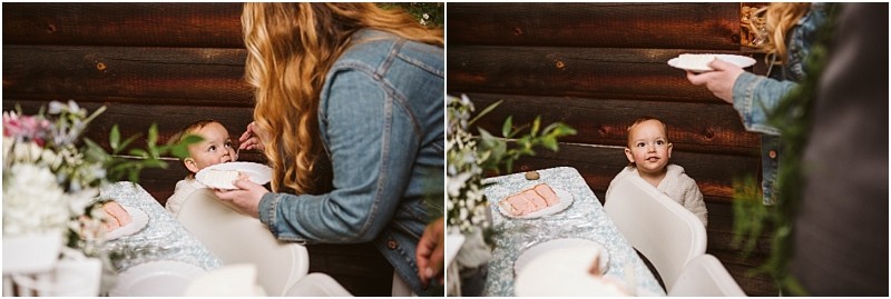 Snohomish & seattle wedding photographer | gsquared weddings photography bathed in warmth a woman shows love with a view as she feeds a young child in a high chair at a table set with plates and flowers Wooden walls frame this cozy machias elopement moment as the child gazes up for the next bite | wedding photo by gsquared weddings