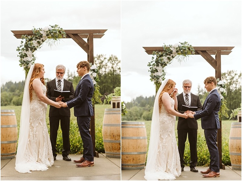 Snohomish & seattle wedding photographer | gsquared weddings photography a bride and groom stand under a wooden arch decorated with greenery during an intimate marionfield farm elopement They hold hands and face each other with an officiant between them while two wine barrels sit nearby | wedding photo by gsquared weddings