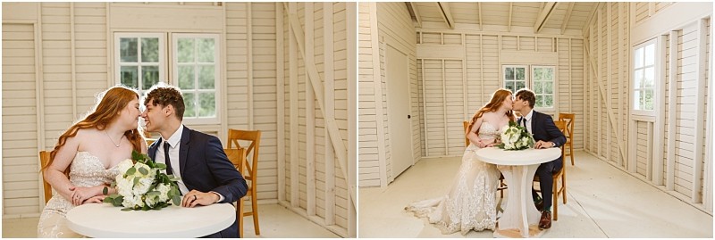 Snohomish & seattle wedding photographer | gsquared weddings photography a bride and groom sit closely at a small round table in a bright white wooden room at marionfield farm elopement holding hands and leaning in for a kiss with a bouquet of flowers on the table | wedding photo by gsquared weddings