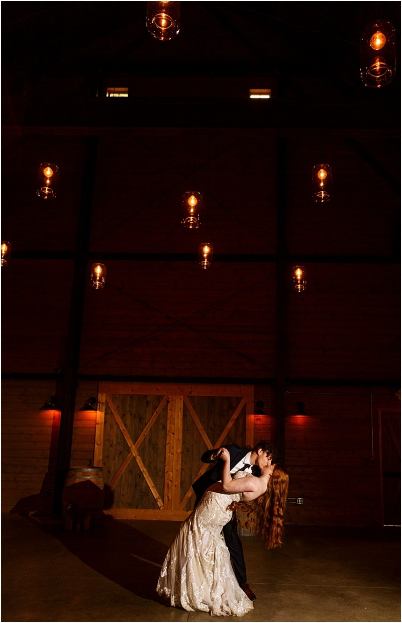 Snohomish & seattle wedding photographer | gsquared weddings photography a couple in formal attire shares a dramatic dance dip under warm hanging lights in a rustic barn with wooden doors at their marionfield farm elopement | wedding photo by gsquared weddings