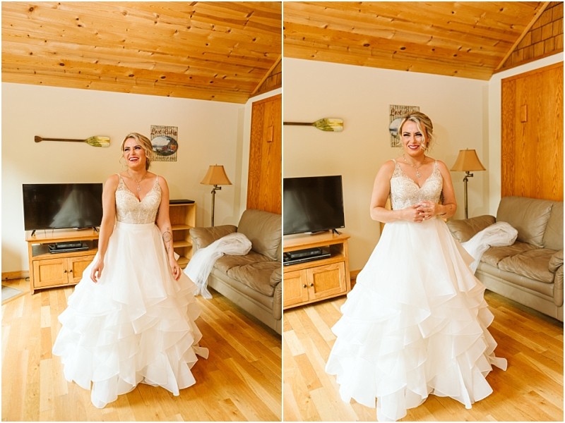 Snohomish & seattle wedding photographer | gsquared weddings photography a bride in a white ruffled wedding dress stands in a cozy wood paneled living room with tan furniture tv and wall decor She smiles and poses for the camera during her intimate methow elopement | wedding photo by gsquared weddings