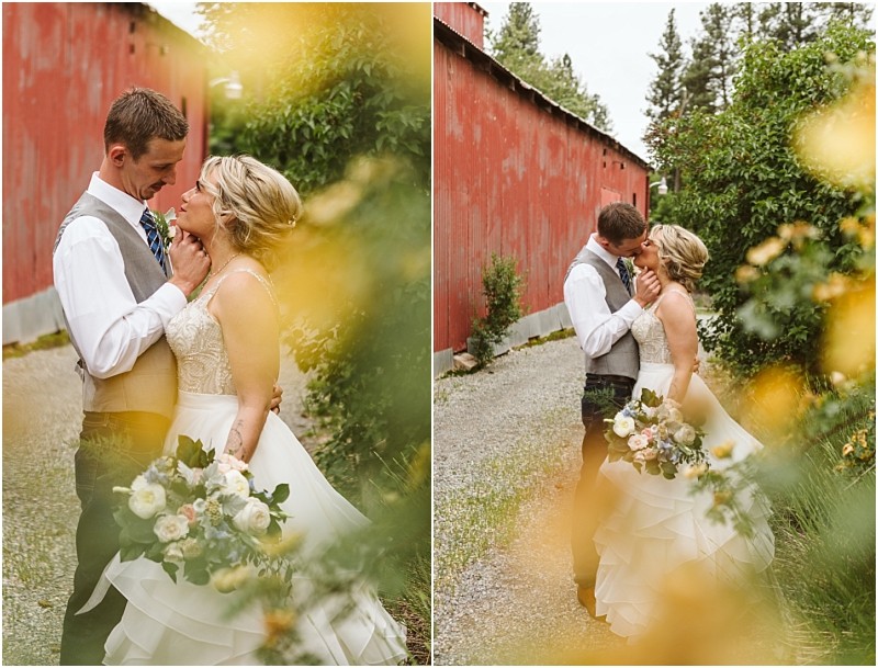 Snohomish & seattle wedding photographer | gsquared weddings photography a bride and groom embrace outdoors beside a rustic red building surrounded by greenery and yellow flowers During their methow elopement the bride holds a bouquet of white and peach flowers as they share a romantic intimate moment | wedding photo by gsquared weddings