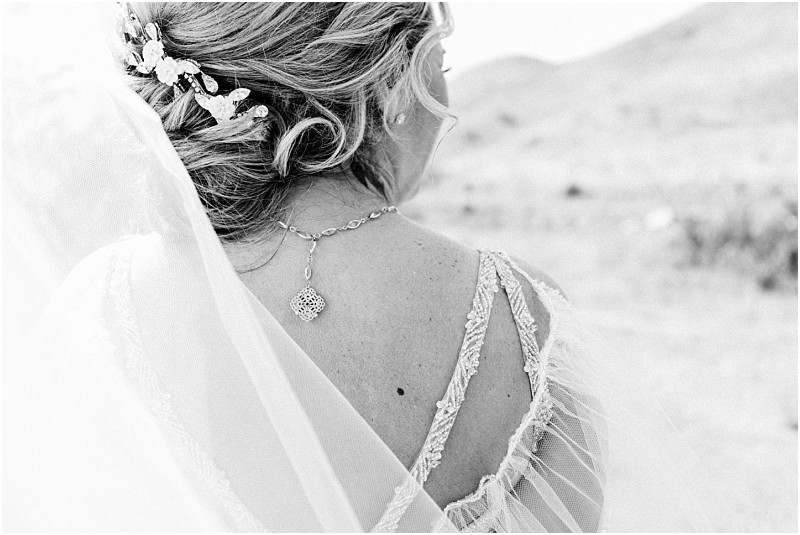 Snohomish & seattle wedding photographer | gsquared weddings photography black and white photo of a bride from behind showcasing her lace wedding dress delicate necklace and ornate hairpiece in her styled haira perfect capture for a methow elopement with a sheer veil draped over her shoulder | wedding photo by gsquared weddings