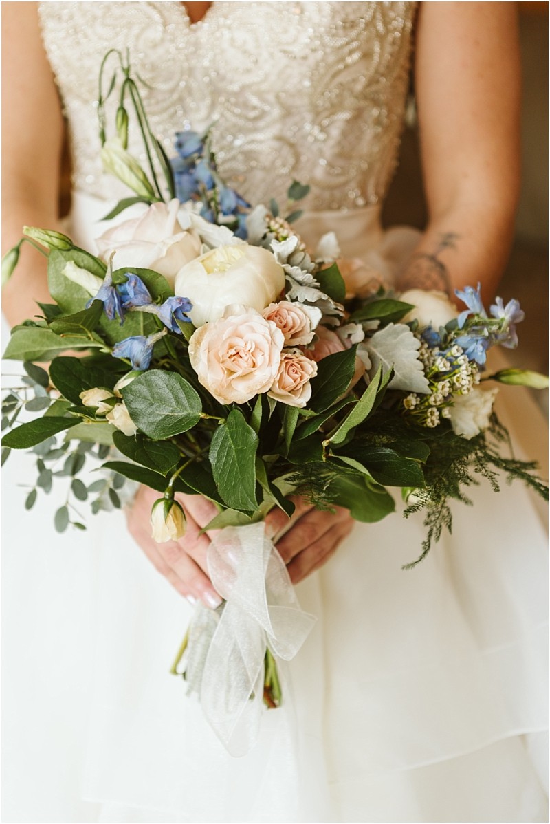 Snohomish & seattle wedding photographer | gsquared weddings photography a bride in a beaded gown holds a bouquet of pale pink roses white flowers blue blooms and greenery tied with a sheer white ribbonperfect for an intimate methow elopement | wedding photo by gsquared weddings