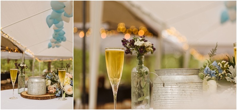 Snohomish & seattle wedding photographer | gsquared weddings photography a close up of a decorated table under a white tent at a methow elopement featuring a metal pail champagne glasses and glass bottles with small flower arrangements Blue balloons and string lights create a festive backdrop | wedding photo by gsquared weddings