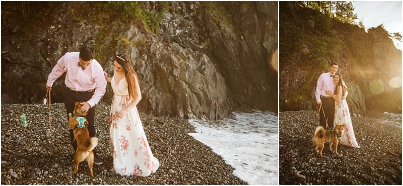 Snohomish & seattle wedding photographer | gsquared weddings photography a couple in dressy attire walks their dog on a rocky beach by the ocean during their deception pass engagement session with cliffs in the background and sunlight streaming in The woman wears a floral dress and the man wears a pink shirt | wedding photo by gsquared weddings