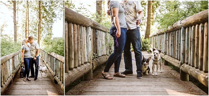 Snohomish & seattle wedding photographer | gsquared weddings photography a couple stands close together on a wooden bridge at deception pass whidbey island holding leashes for two dogs Sunlight filters through the trees creating a warm peaceful engagement scene | wedding photo by gsquared weddings