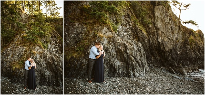 Snohomish & seattle wedding photographer | gsquared weddings photography a couple embraces on a rocky shoreline beneath a steep cliff at deception pass whidbey island Surrounded by trees and rugged terrain they stand with their dogs on the pebbled beach at the base of the cliff captured in a serene engagement moment | wedding photo by gsquared weddings