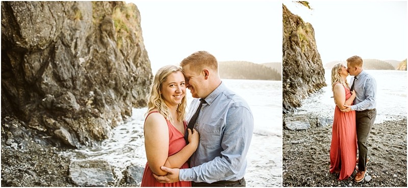 Snohomish & seattle wedding photographer | gsquared weddings photography a couple stands close together on a rocky beach near deception pass smiling and embracing with the ocean in the background The woman wears a coral dress the man a blue shirt and tiecapturing their whidbey island engagement | wedding photo by gsquared weddings