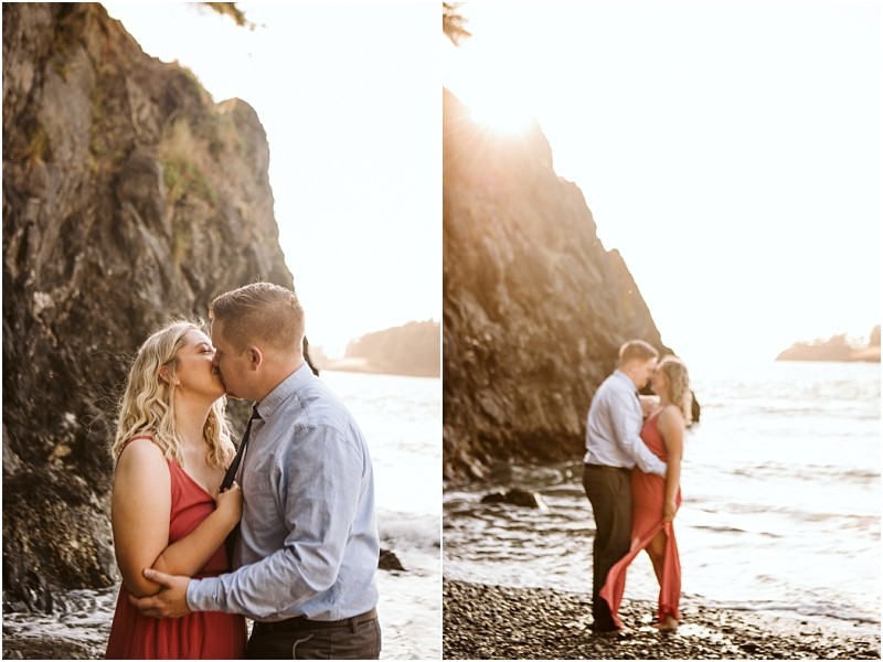Snohomish & seattle wedding photographer | gsquared weddings photography a couple stands by a rocky beach at deception pass sharing a kiss and embrace The woman in a red dress and the man in a blue shirt bask in the suns golden glow with whidbey island cliffs and sparkling water as their engagement backdrop | wedding photo by gsquared weddings