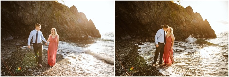 Snohomish & seattle wedding photographer | gsquared weddings photography a couple stands barefoot on the rocky shores of deception pass whidbey island at sunset the man in a shirt and tie the woman in a long red dress They walk together smiling then share a kiss as waves reach their feet during their engagement shoot | wedding photo by gsquared weddings